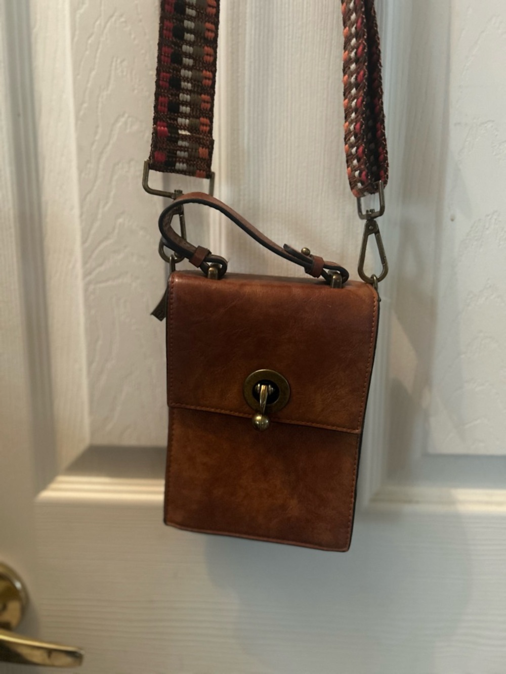 Compact Brown Leather Messenger Bag with Adjustable Woven Strap.